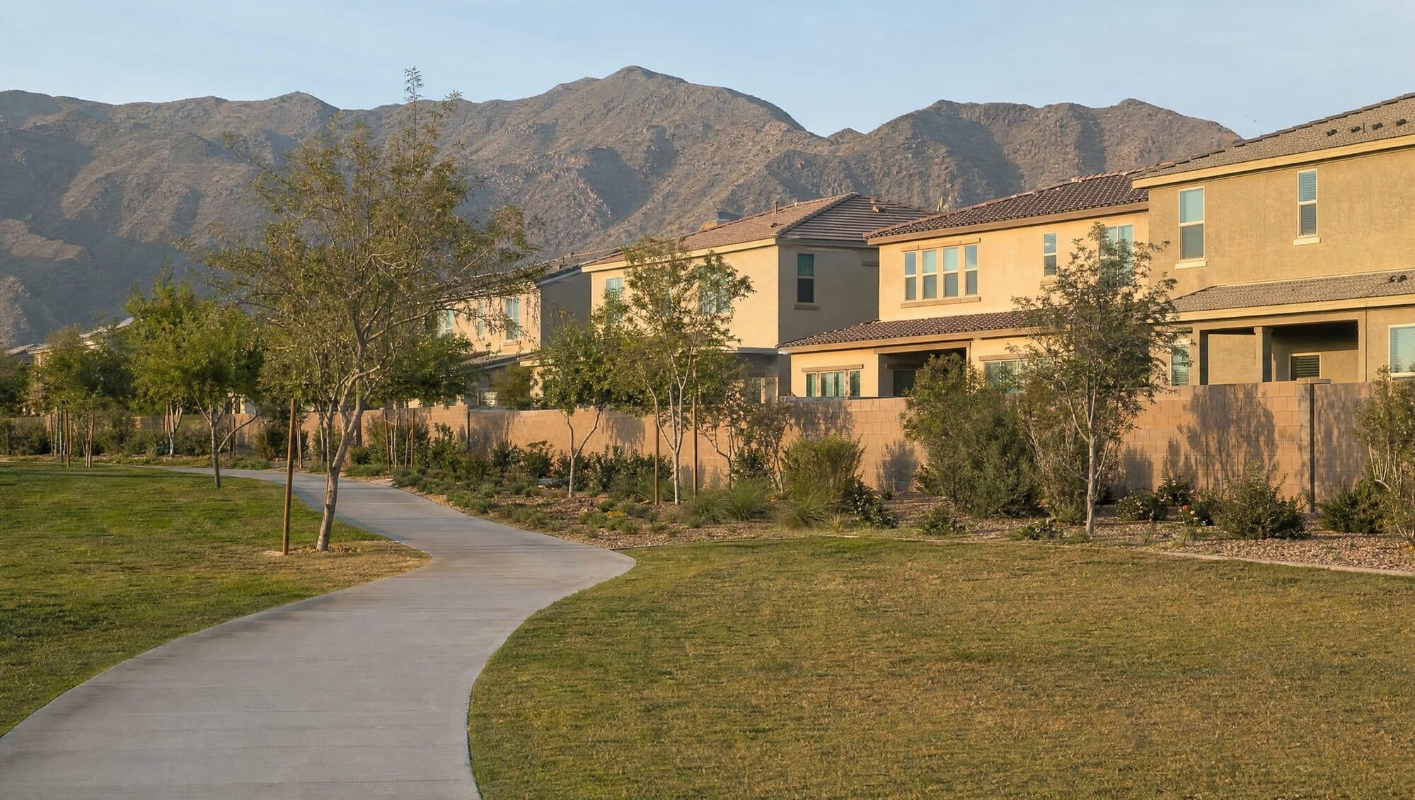 A neighborhood walking path beside new homes with mountains behind